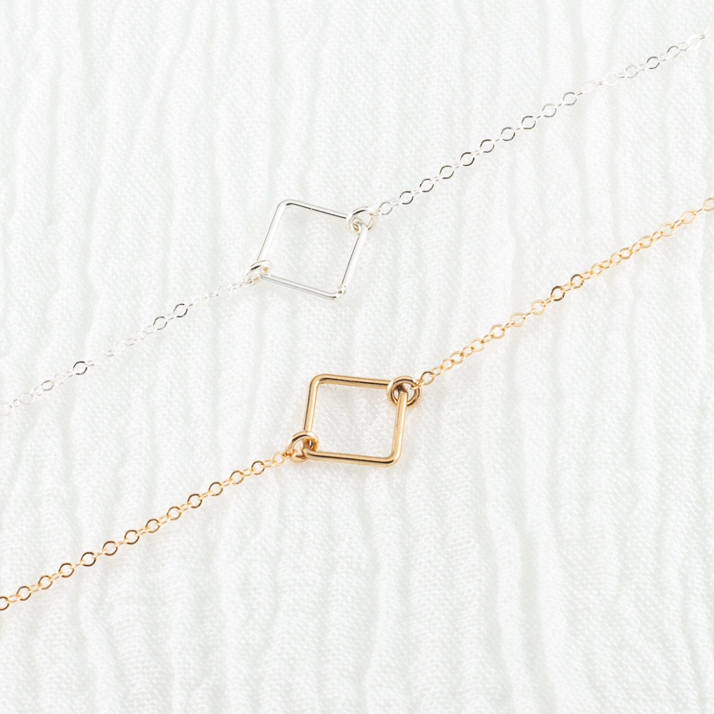 two necklaces sitting on top of a white sheet