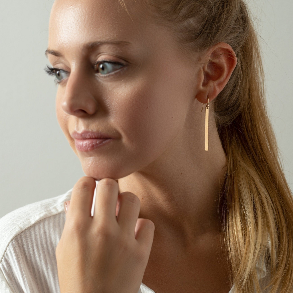 a woman wearing a white shirt and gold earrings