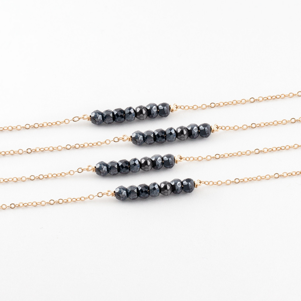 a set of three black beads on a gold chain