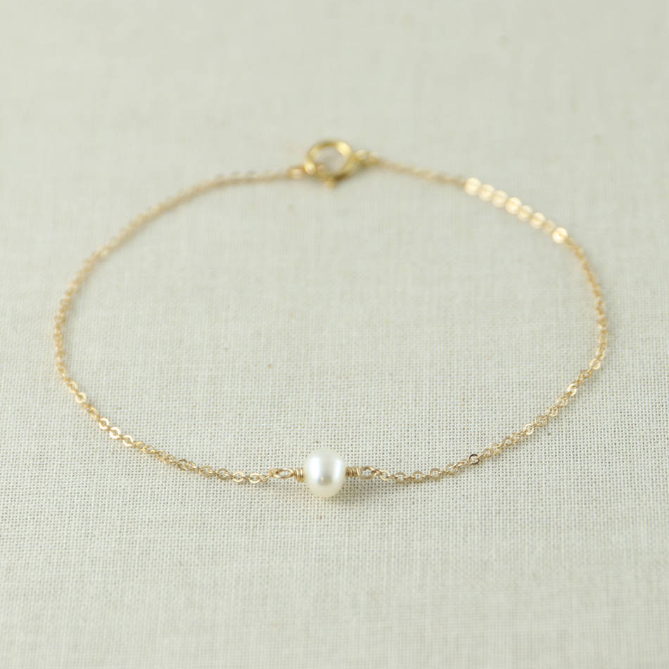 a gold bracelet with a single pearl