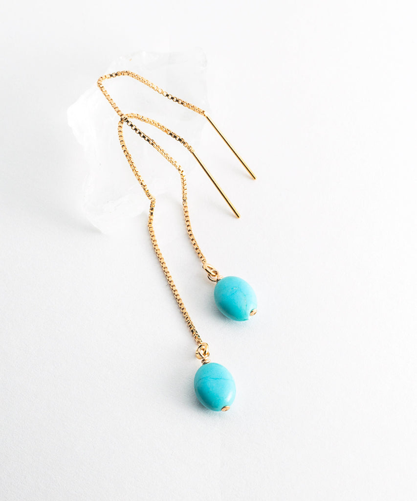 a pair of blue beads hanging from a gold chain