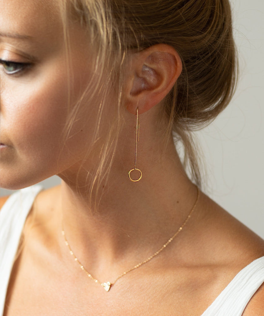 a woman wearing a white tank top and a gold necklace