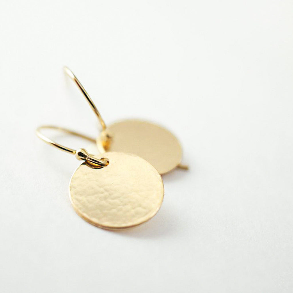 a pair of gold earrings on a white surface