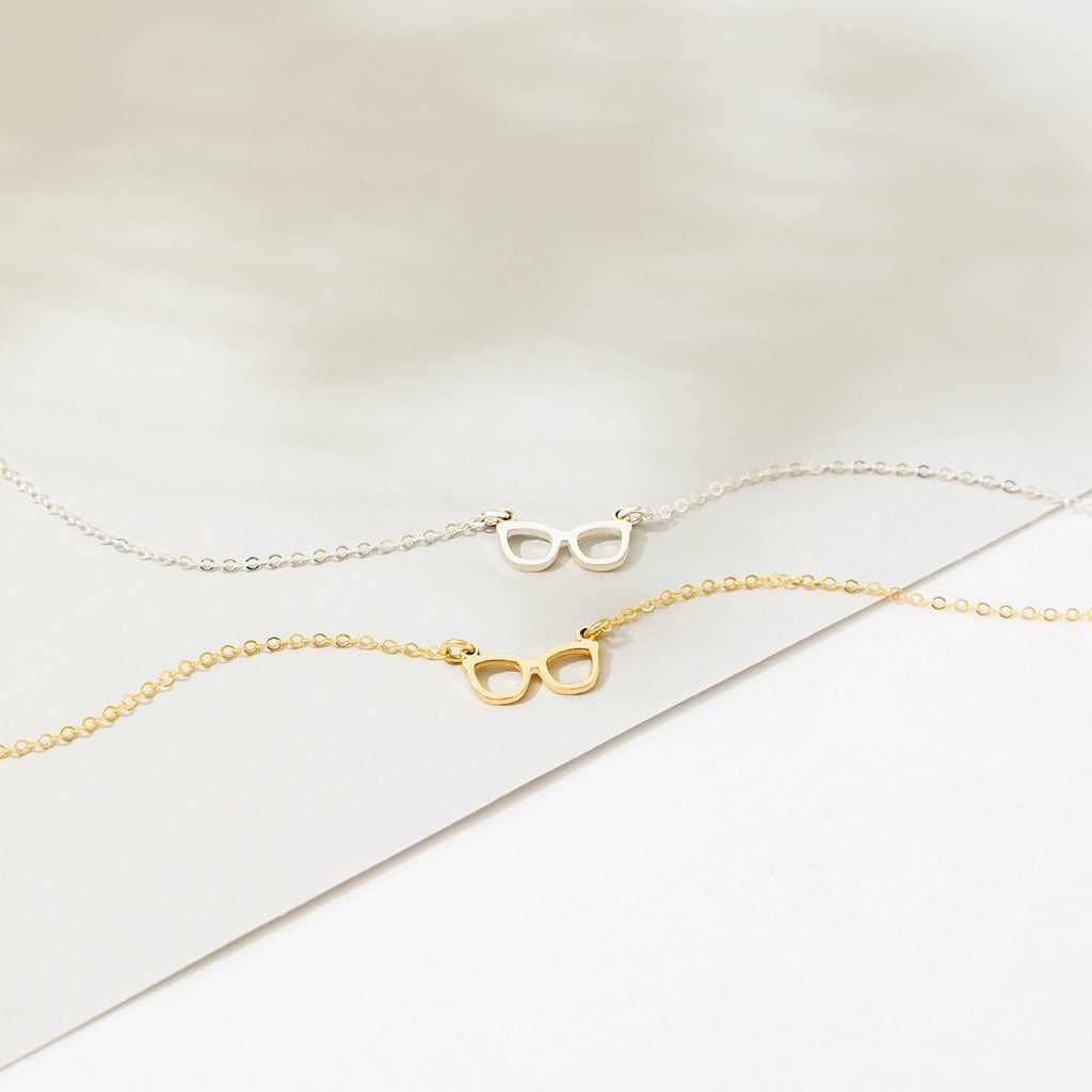 a pair of glasses on a chain on a white surface