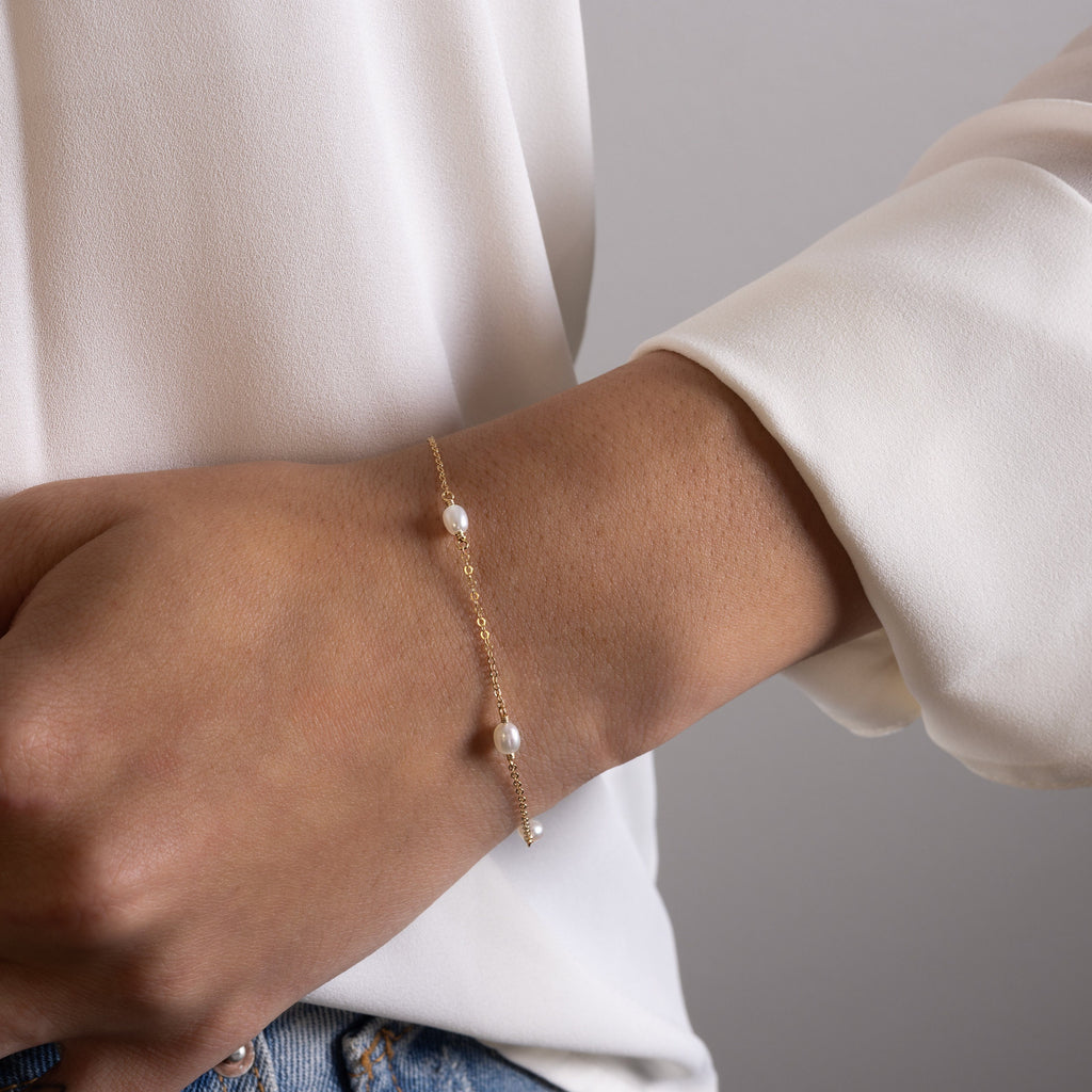 a woman wearing a gold bracelet with pearls