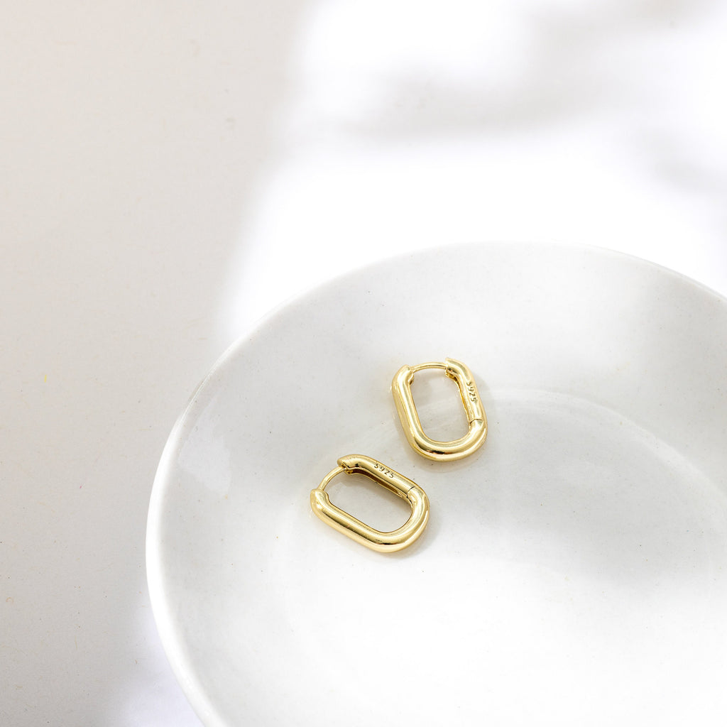 a white plate with a pair of gold earrings on it