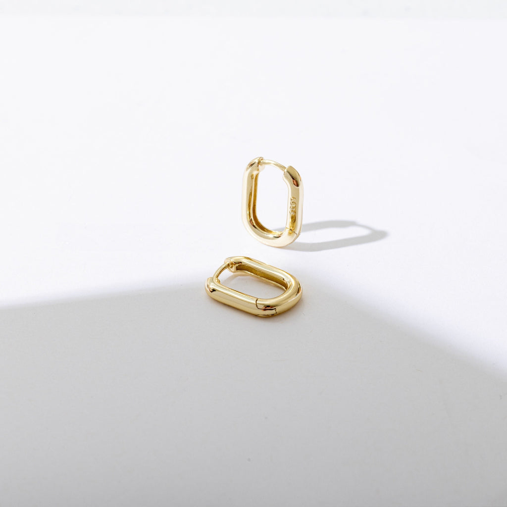 a pair of gold earrings sitting on top of a white surface
