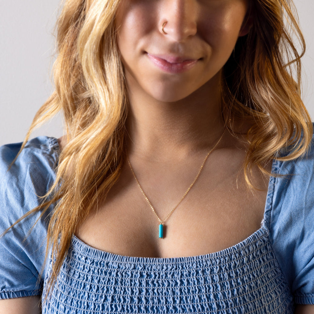 a woman wearing a blue shirt and a necklace