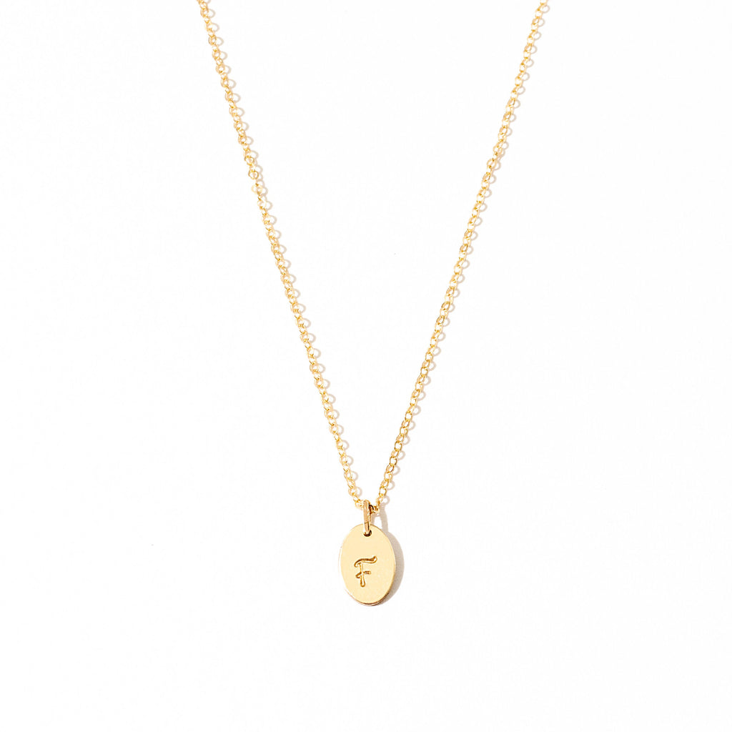 a gold necklace with a small initial on it