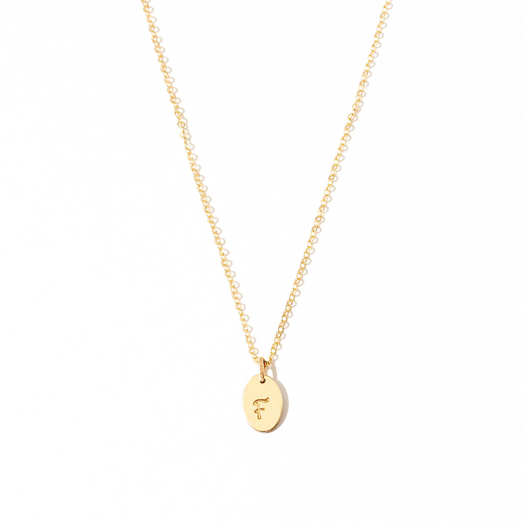 a gold necklace with a small initial on it