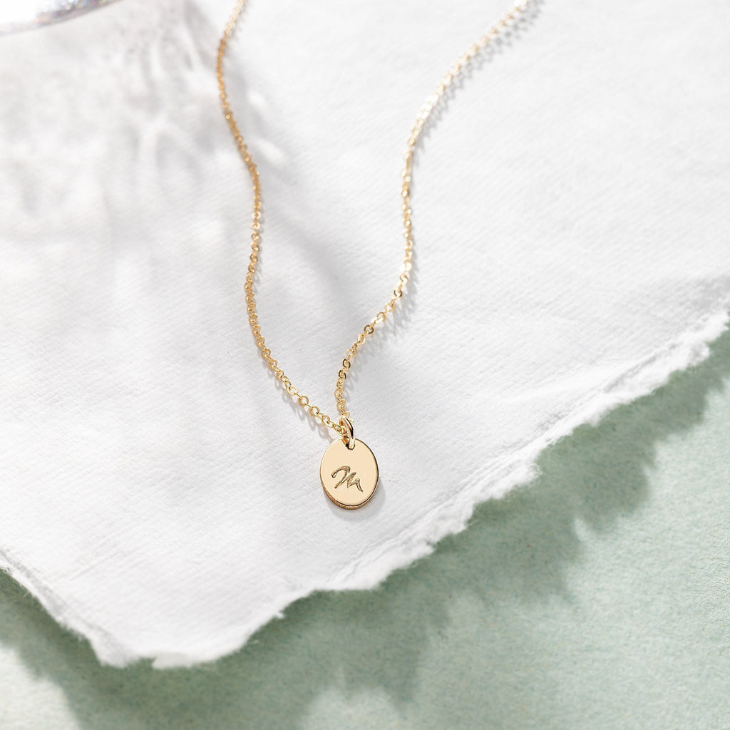a gold necklace with a small initial on it