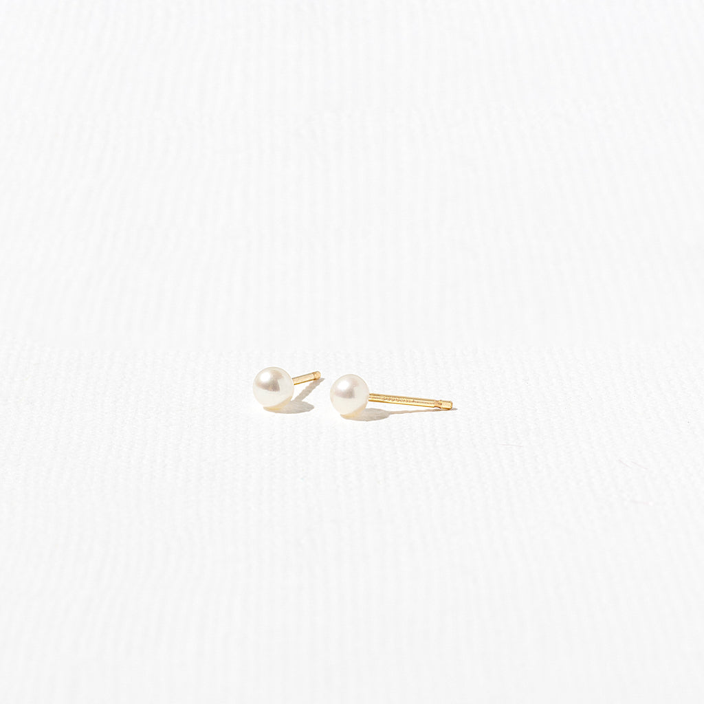 a pair of pearl earrings sitting on top of a white surface
