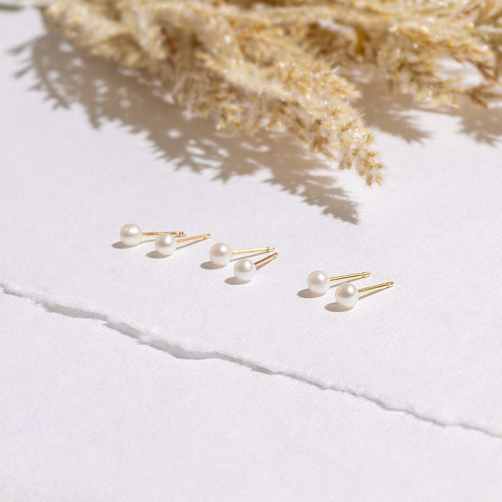 three pairs of pearl earrings sitting on top of a table