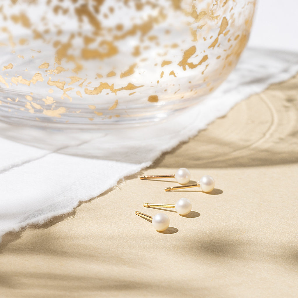 a pair of gold and white earrings sitting on top of a table