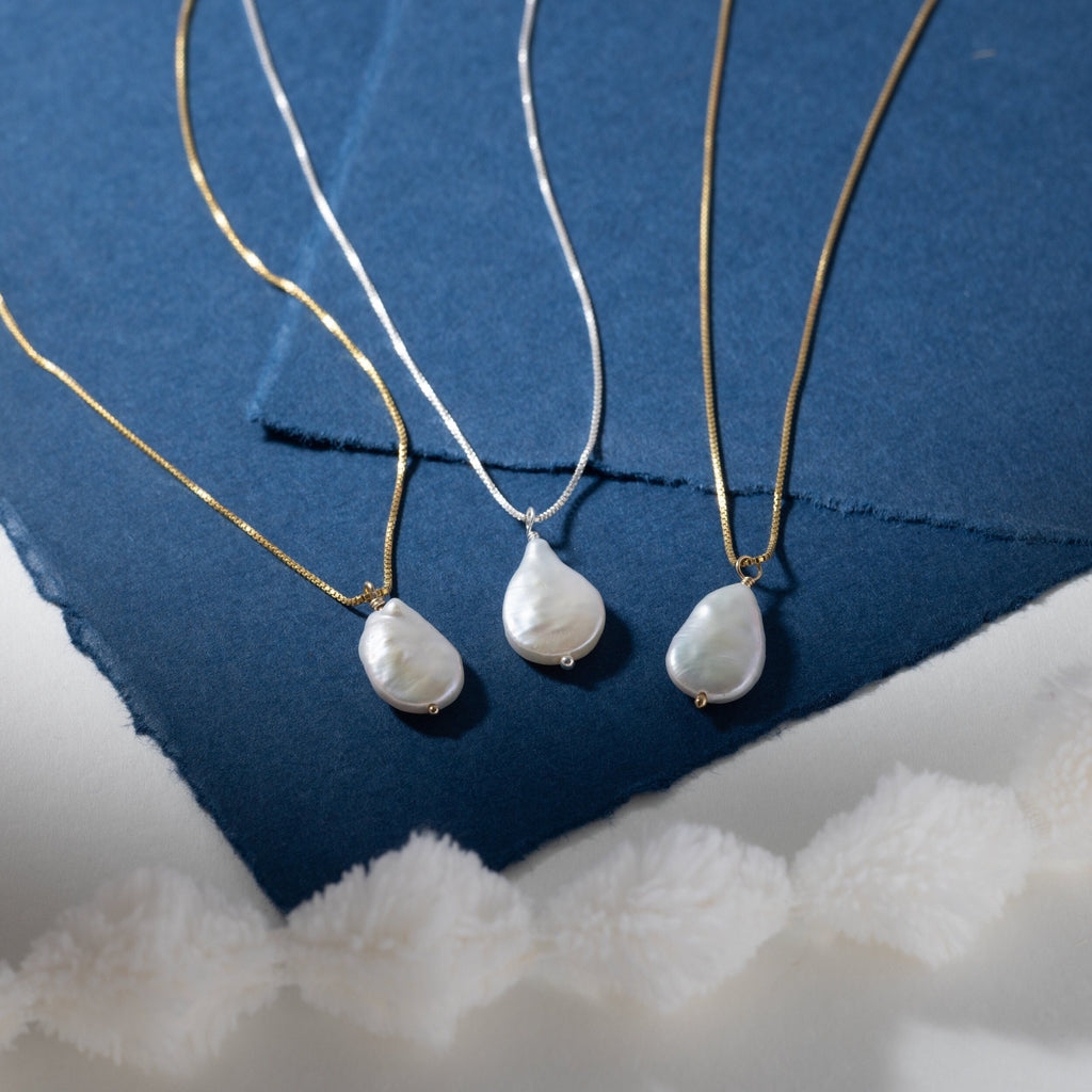 a group of three necklaces sitting on top of a blue piece of paper