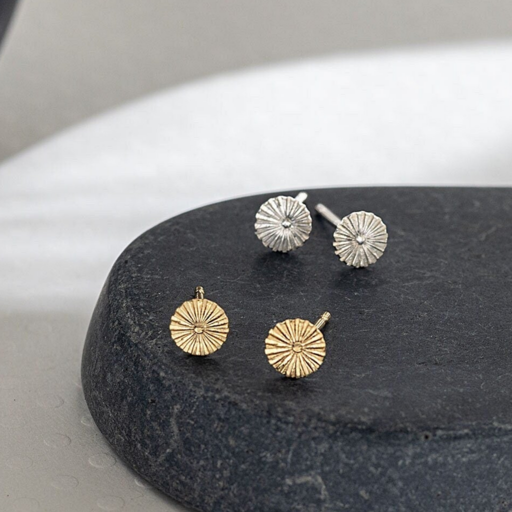 Pair of gold and silver earrings on a dark stone surface
