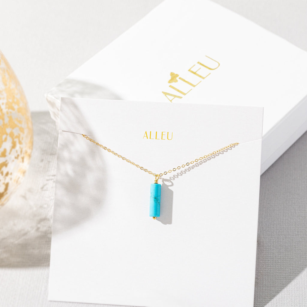 a necklace with a blue rectangle pendant on a card
