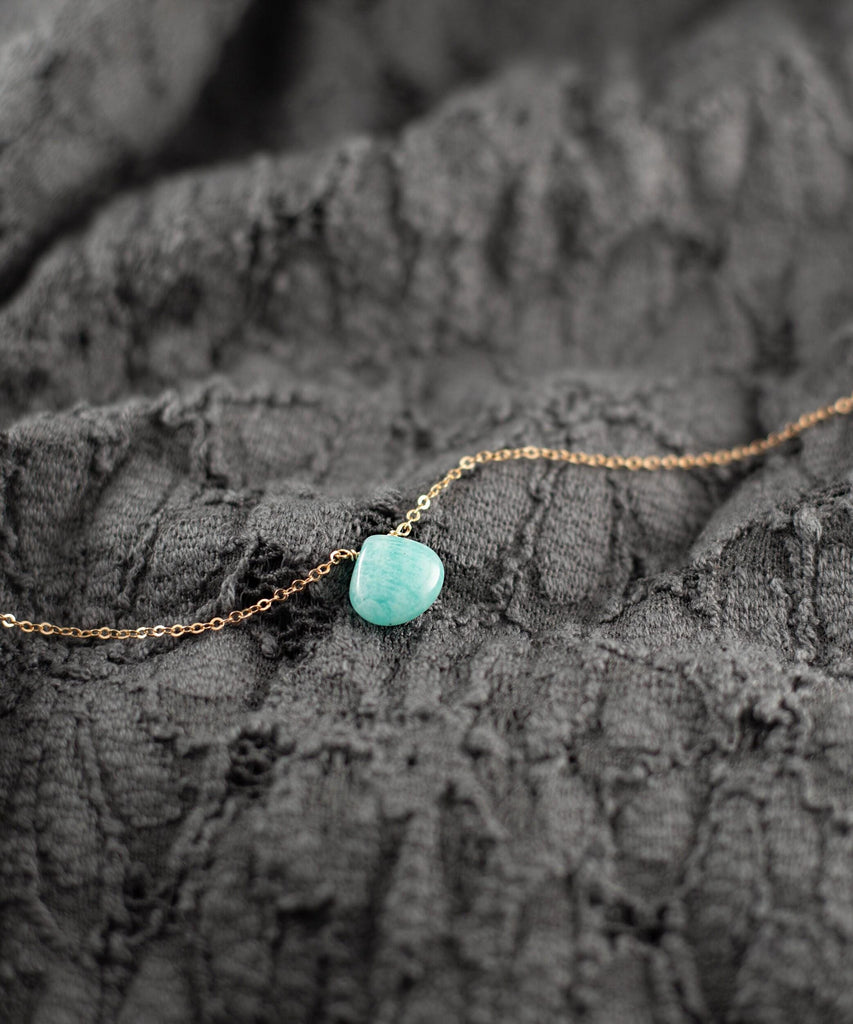 a gold chain with a turquoise stone on it