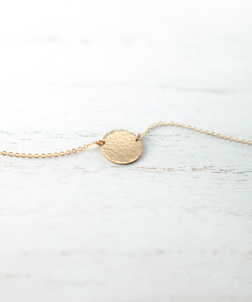 a gold necklace with a disc on it