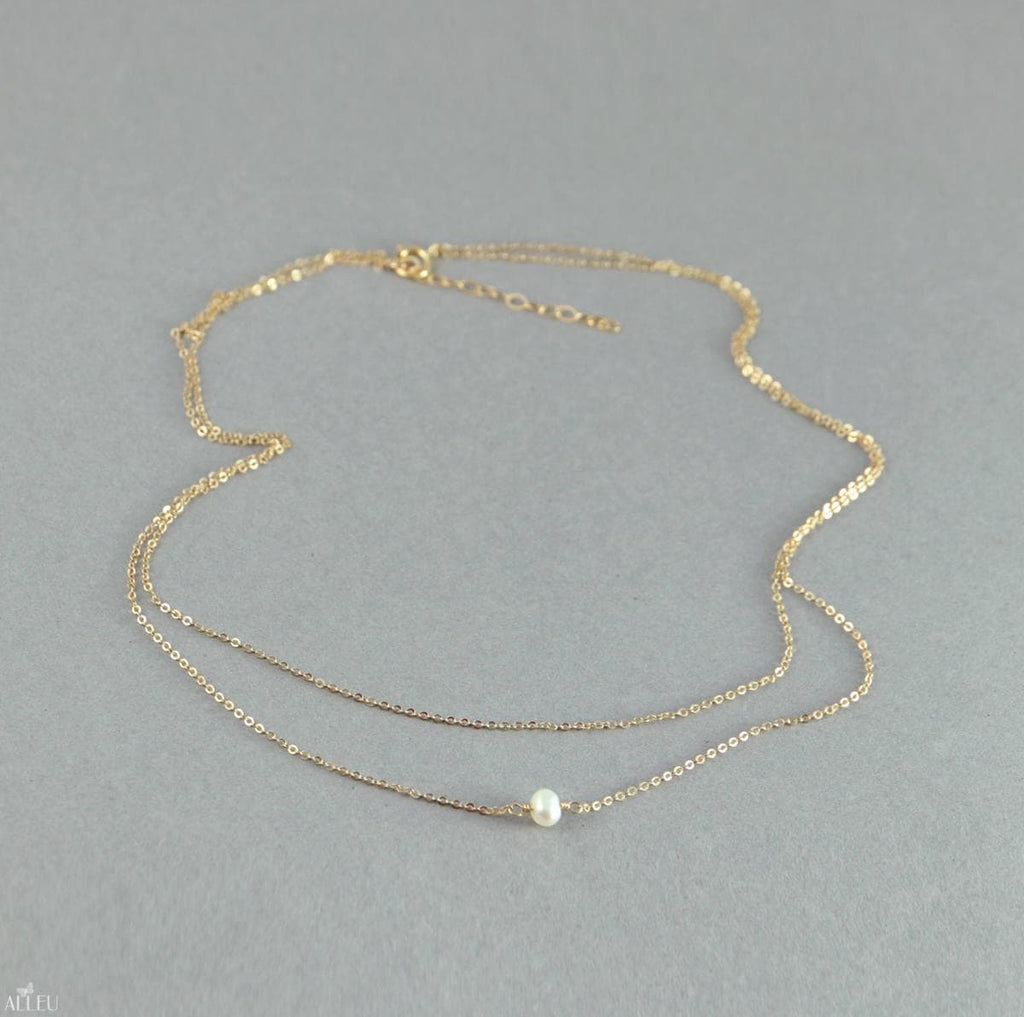 a gold necklace with a pearl on it