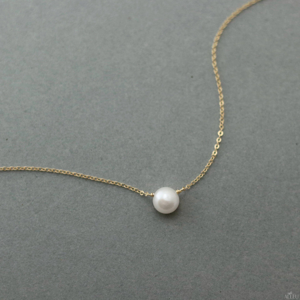 a necklace with a white pearl hanging from it