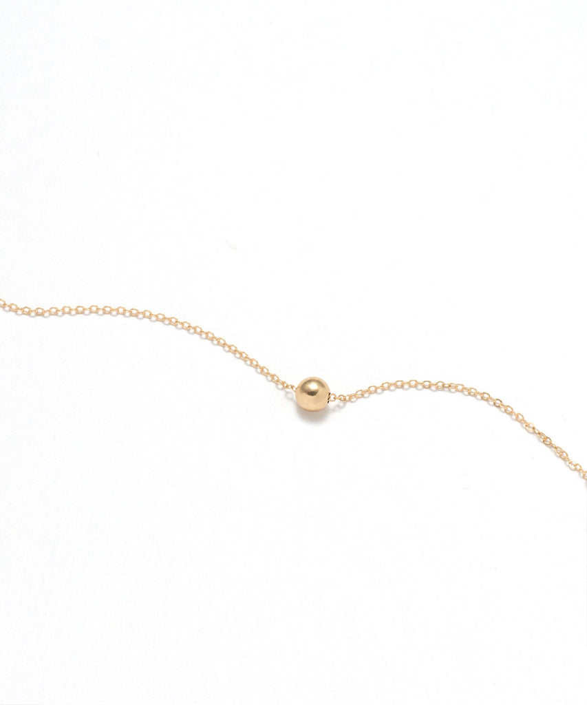 a gold necklace with a ball on it