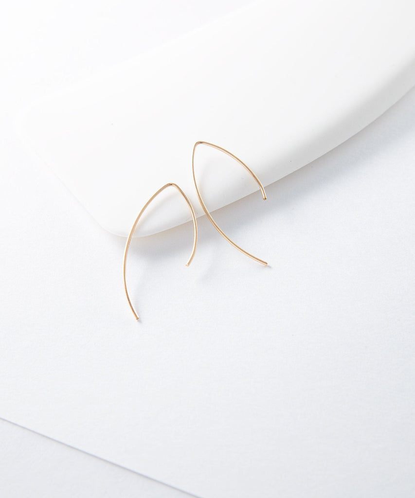 a pair of gold earrings sitting on top of a white surface