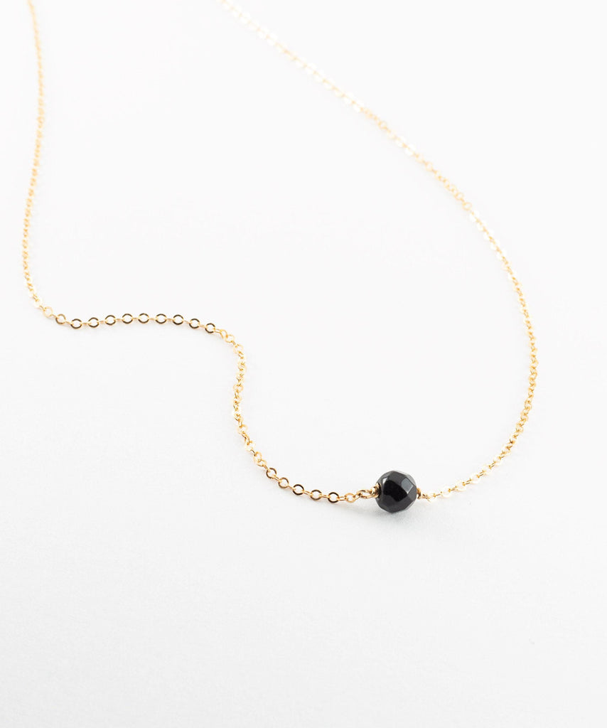 a gold chain with a black bead on it