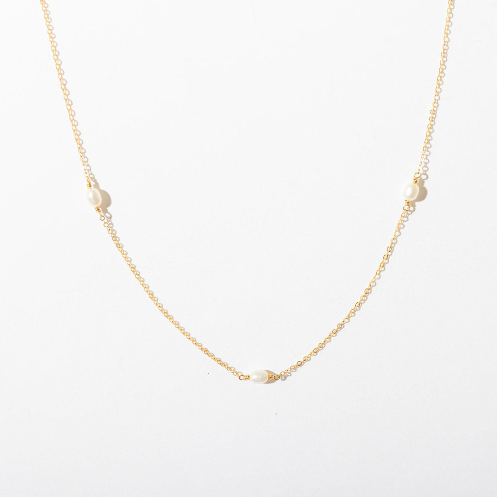 a gold necklace with pearls on a white background