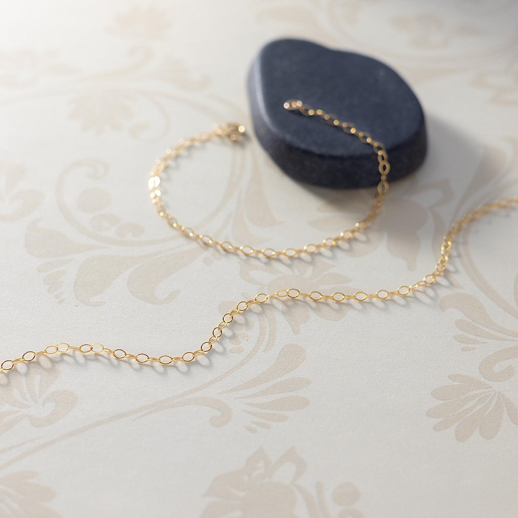 a gold chain is on a table next to a rock