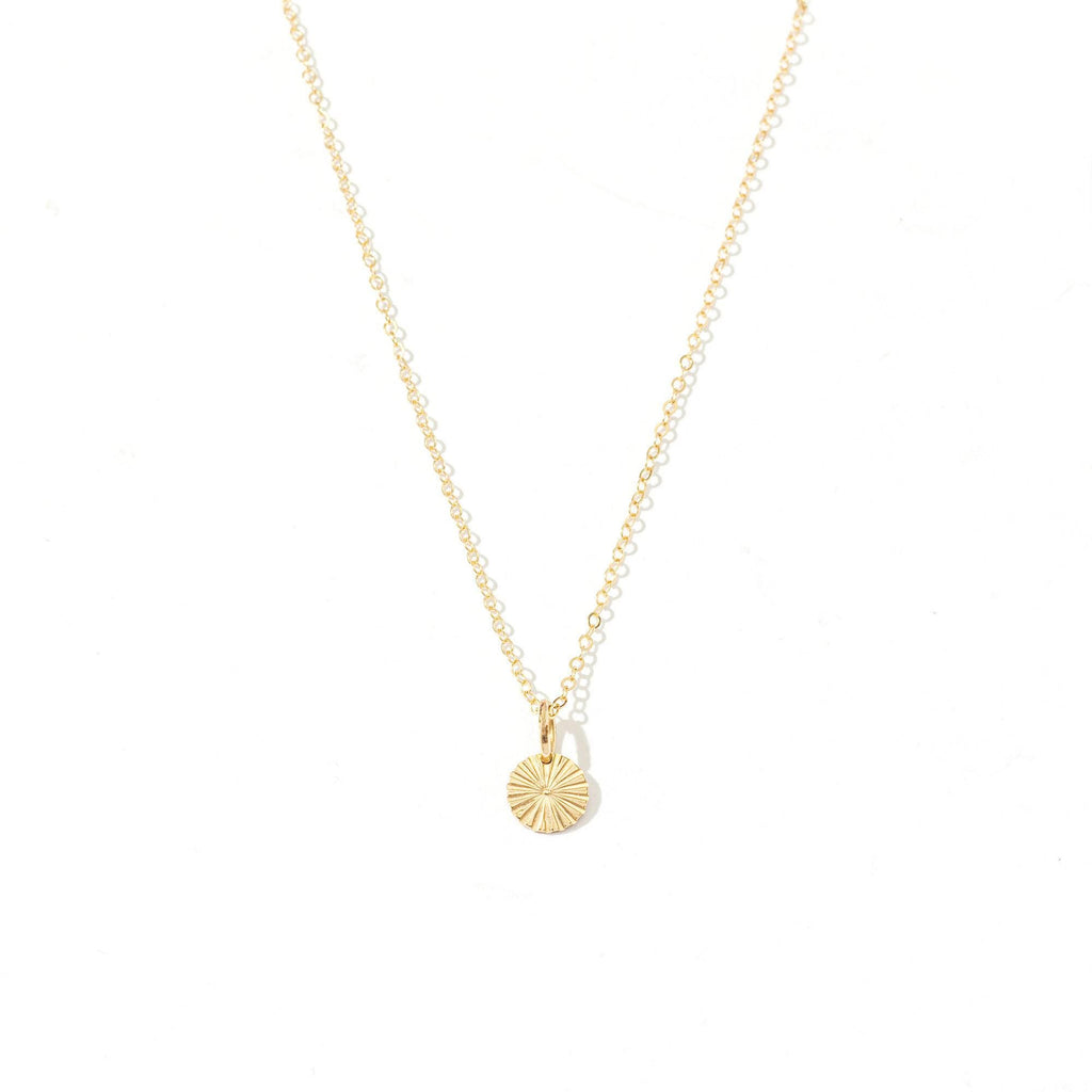 a gold necklace with a small disc on it