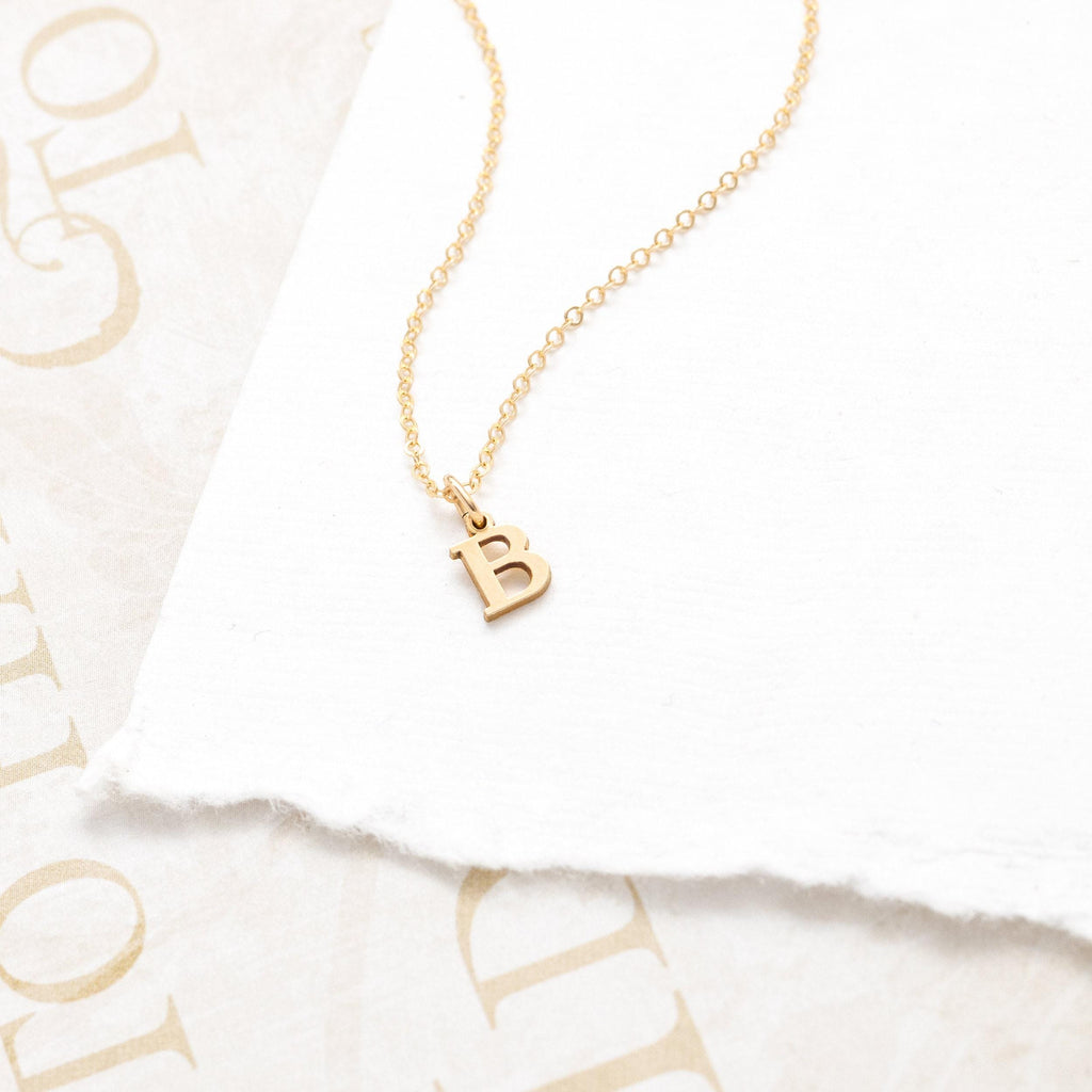 a gold necklace with the letter b on it