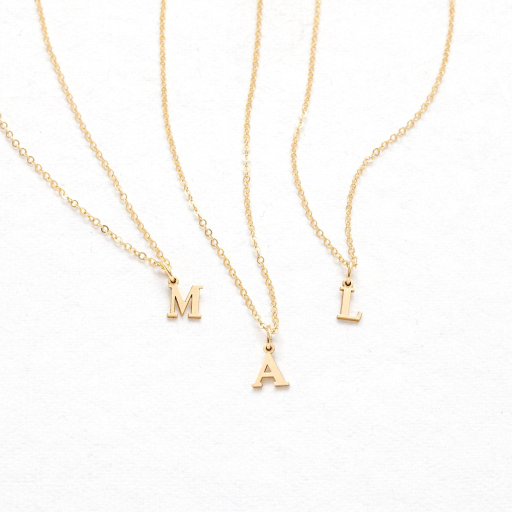 three initial necklaces on a white background