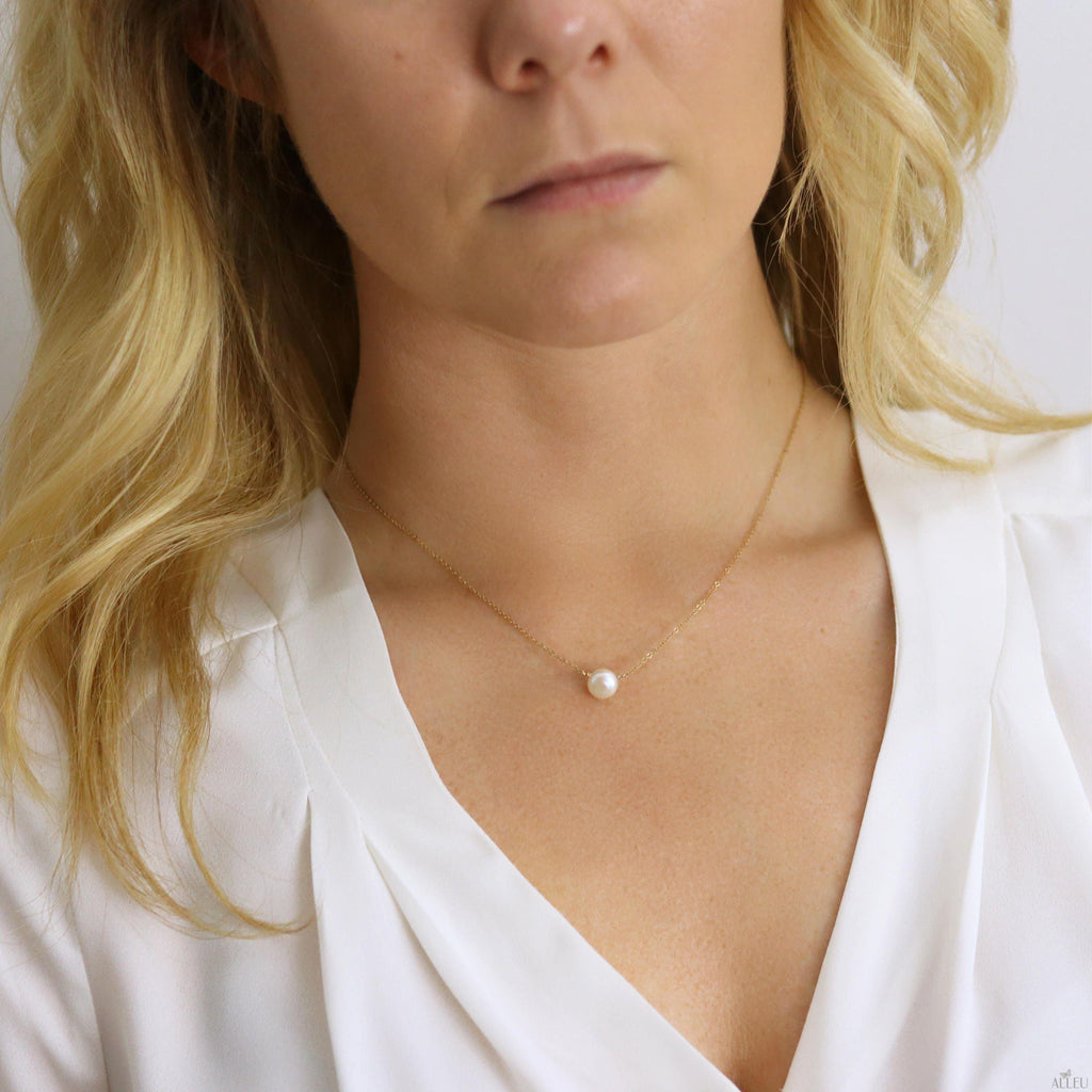 a woman wearing a white shirt and a pearl necklace