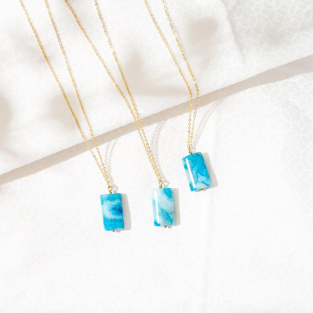 three necklaces with blue stones hanging from a gold chain