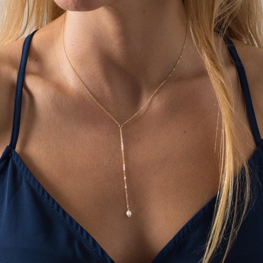a woman wearing a necklace with a pearl