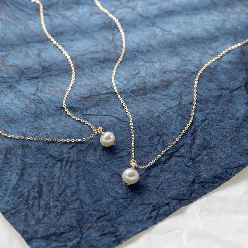 a close up of two necklaces on a blue cloth