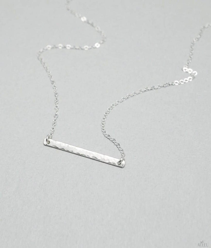 a silver bar necklace on a silver chain