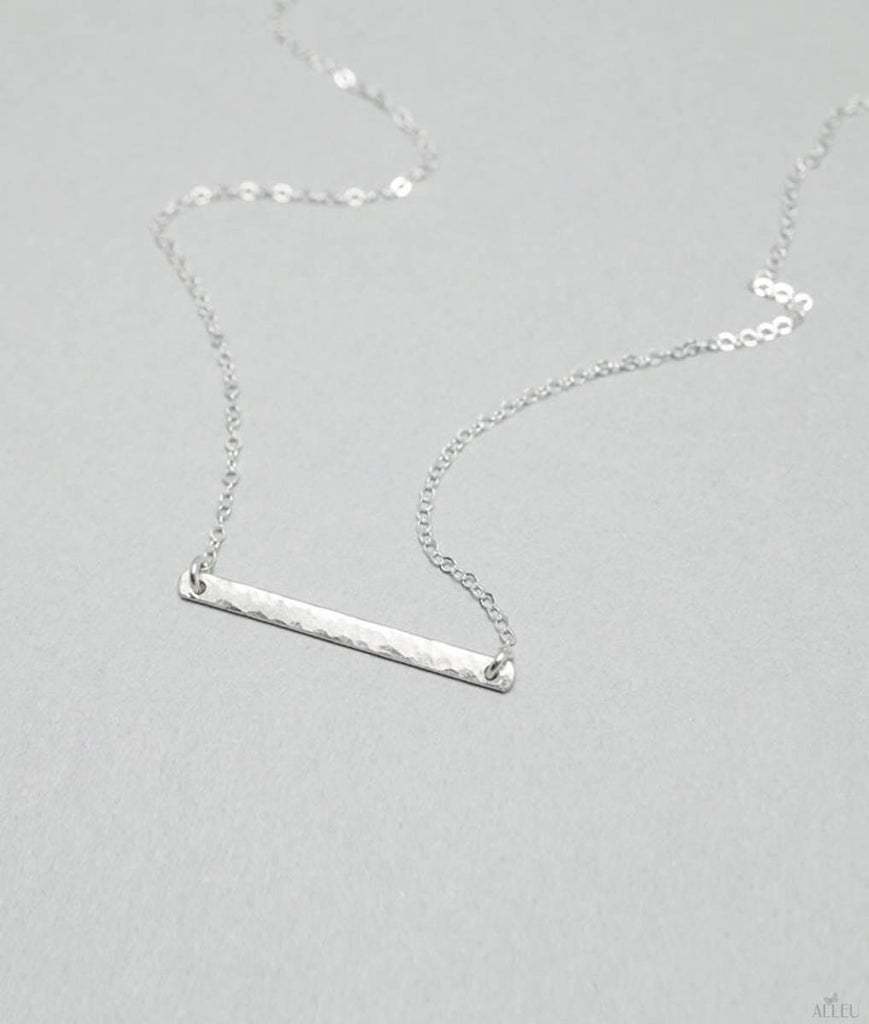 a silver bar necklace on a silver chain