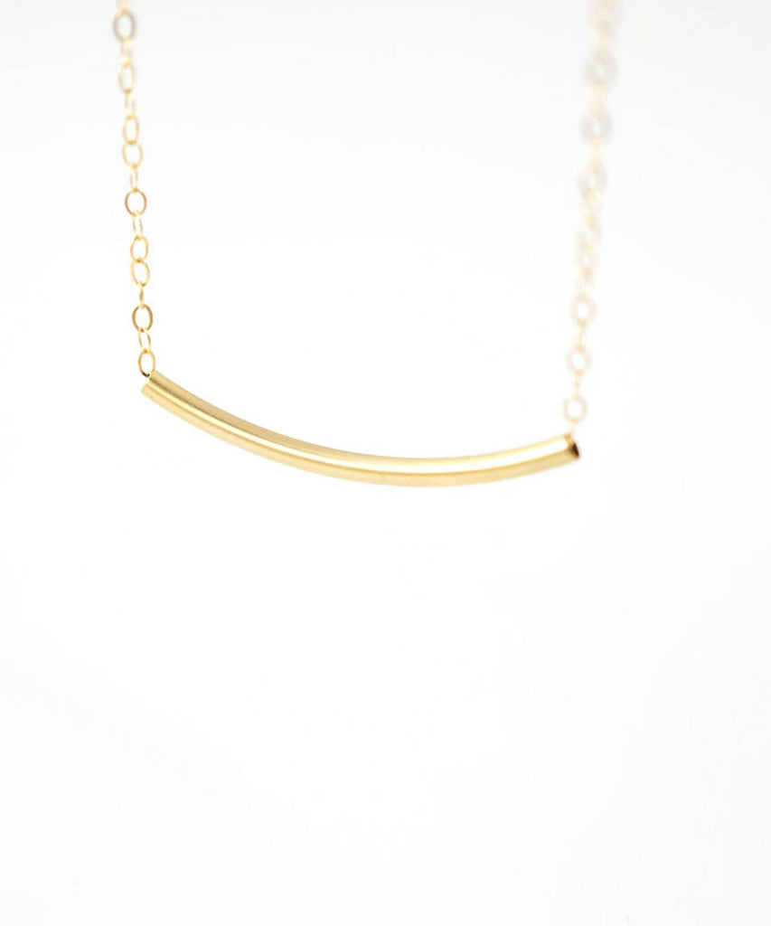 a gold bar necklace on a white background