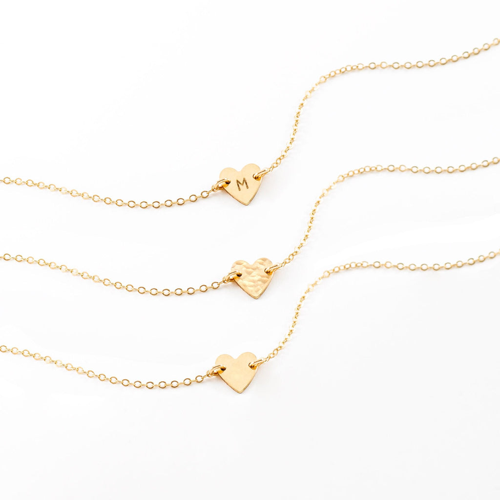 a couple of gold necklaces sitting on top of a white surface