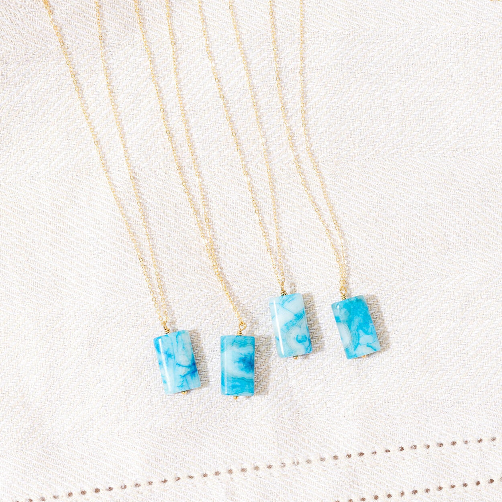 three necklaces with blue and white designs on them