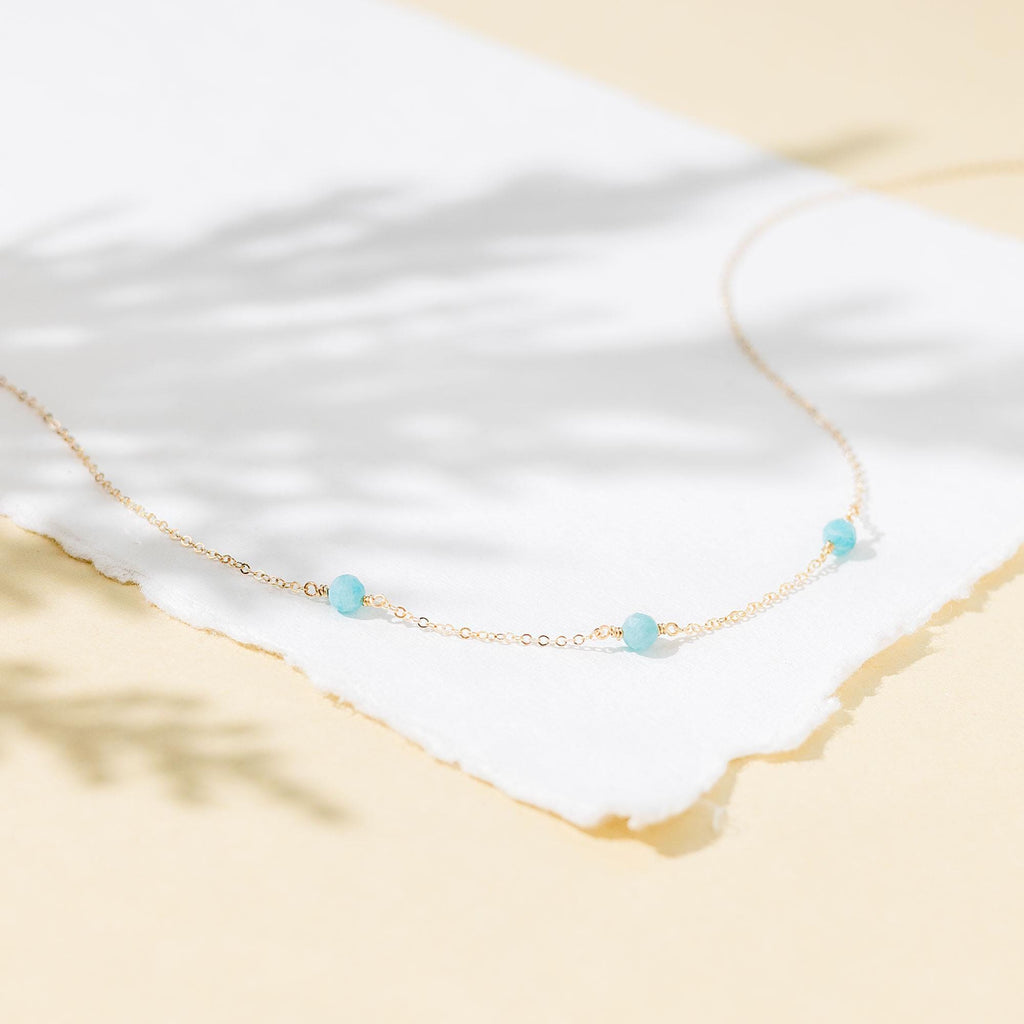 a necklace with three beads on a white piece of paper