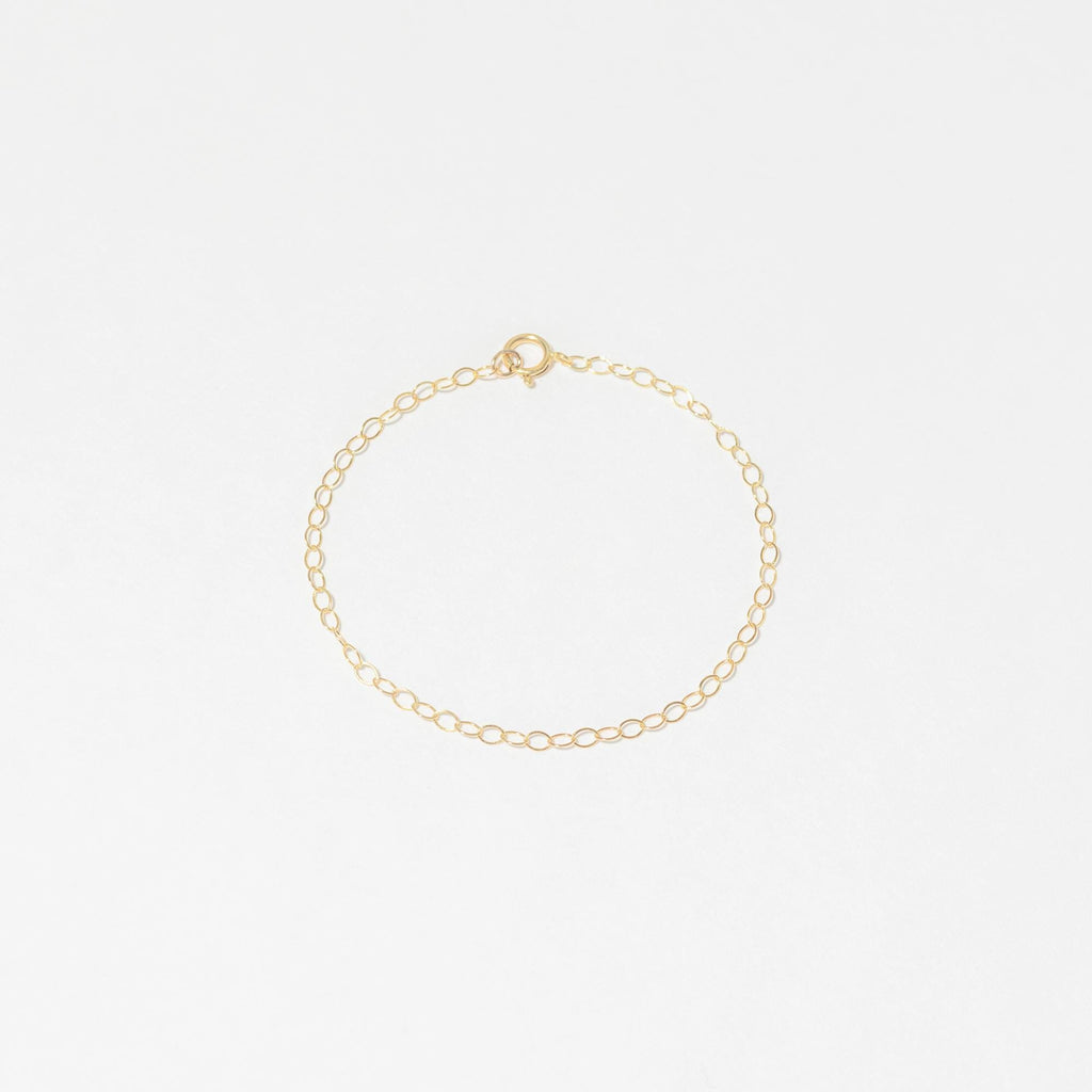 a gold chain bracelet with a tiny heart charm