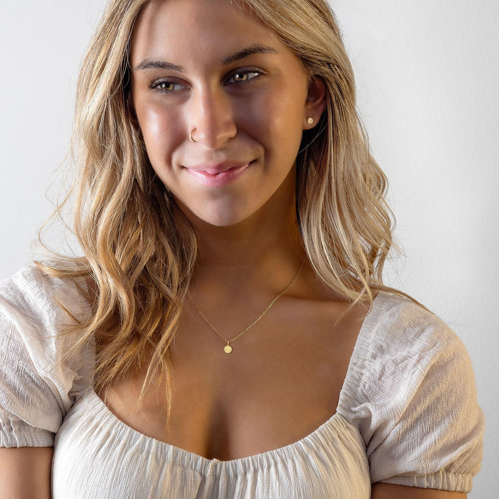 a woman wearing a white shirt and a gold necklace