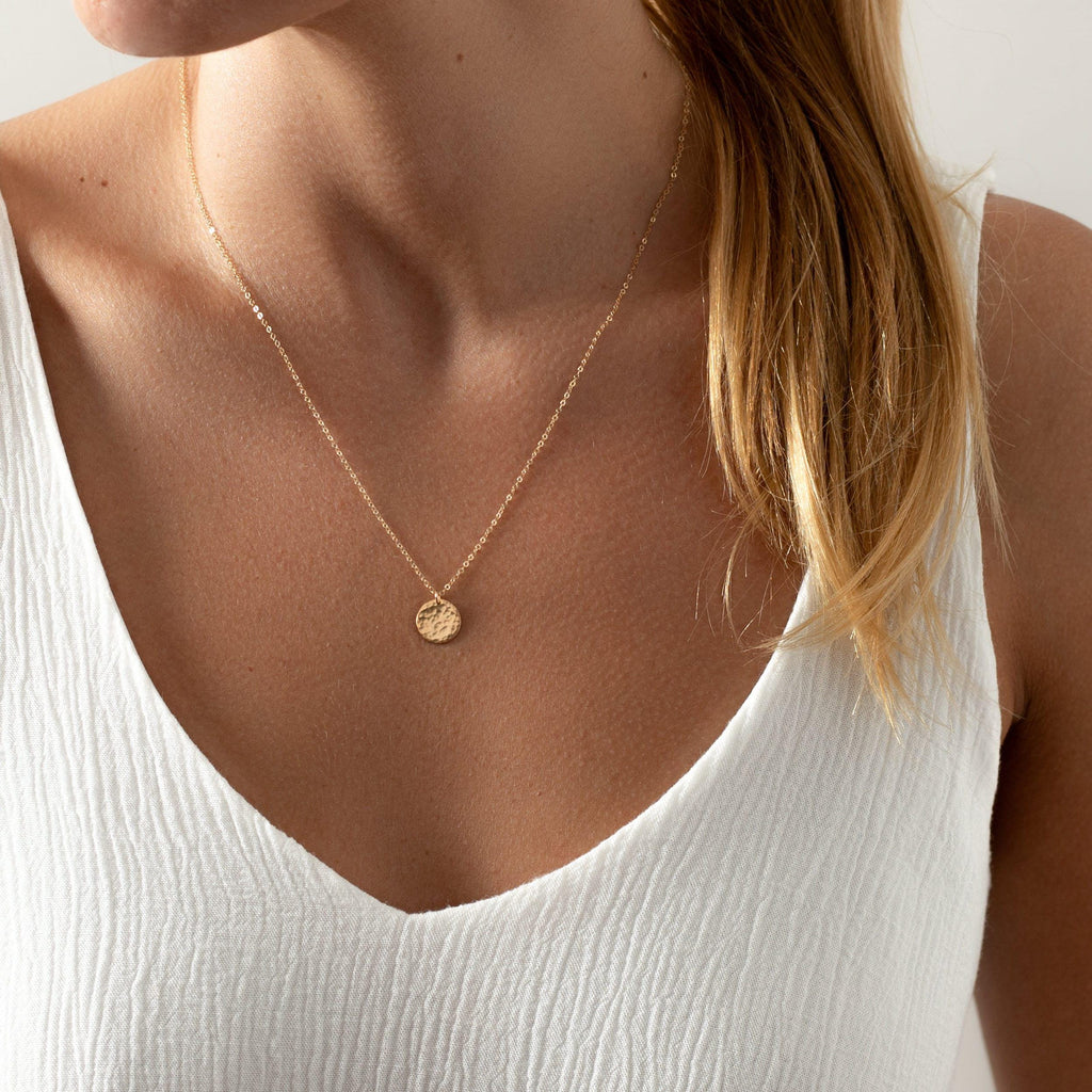 a woman wearing a necklace with a disc on it