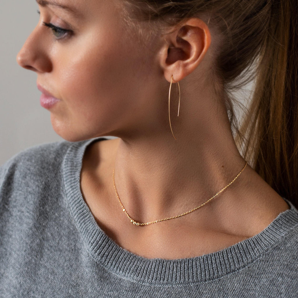 a woman wearing a pair of gold earrings