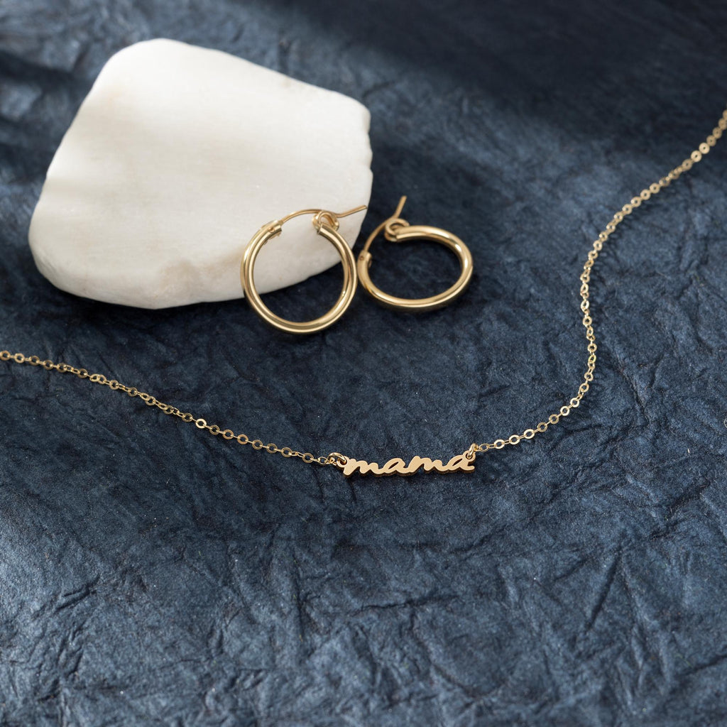 a pair of gold hoop earrings sitting on top of a rock