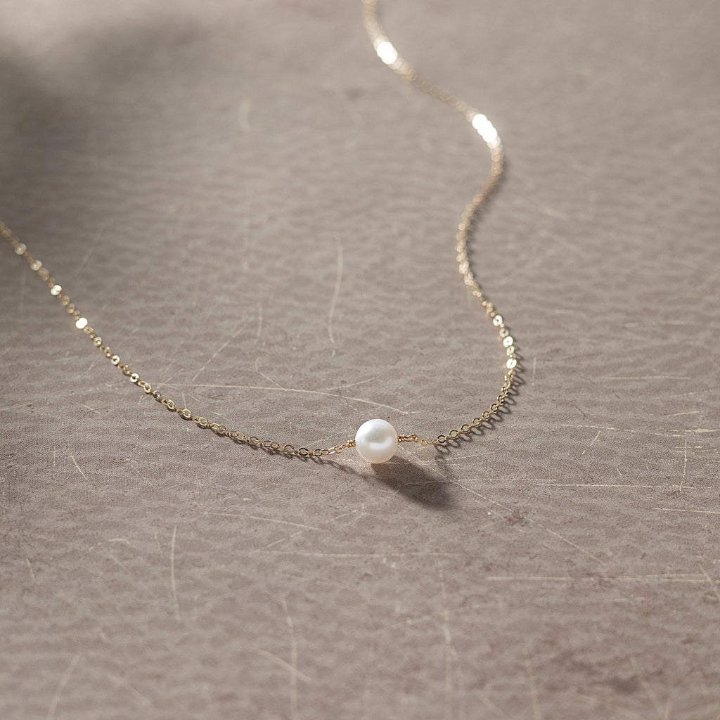a necklace with a single pearl hanging from it