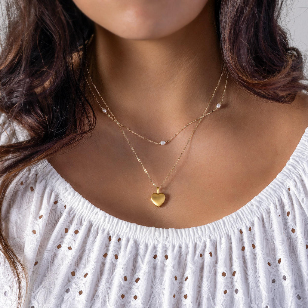 a woman wearing a necklace with a heart on it